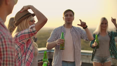 A-women-beautifully-moves-her-hands-in-a-dance.-She-is-dancing-with-her-friend-on-the-roof-in-a-hot-sunny-everning-with-beer.